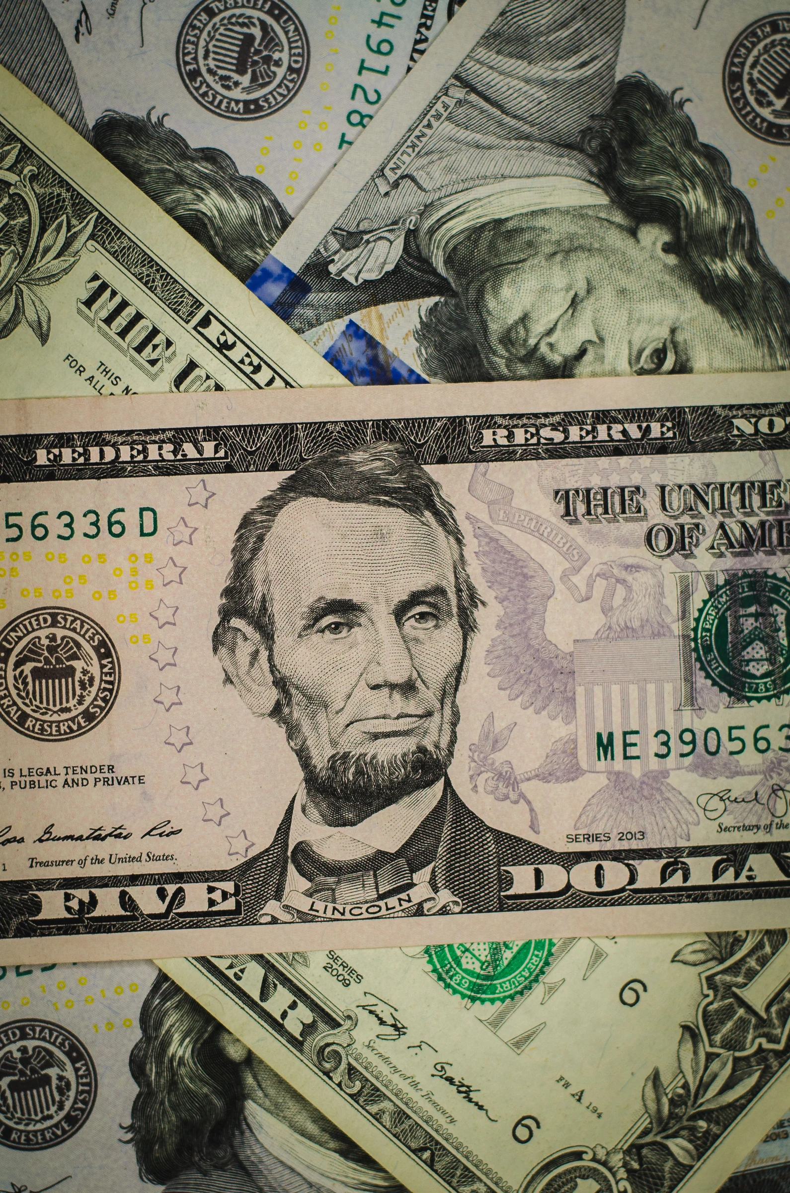 An ordinary five-dollar bill among overlapping U.S. banknotes